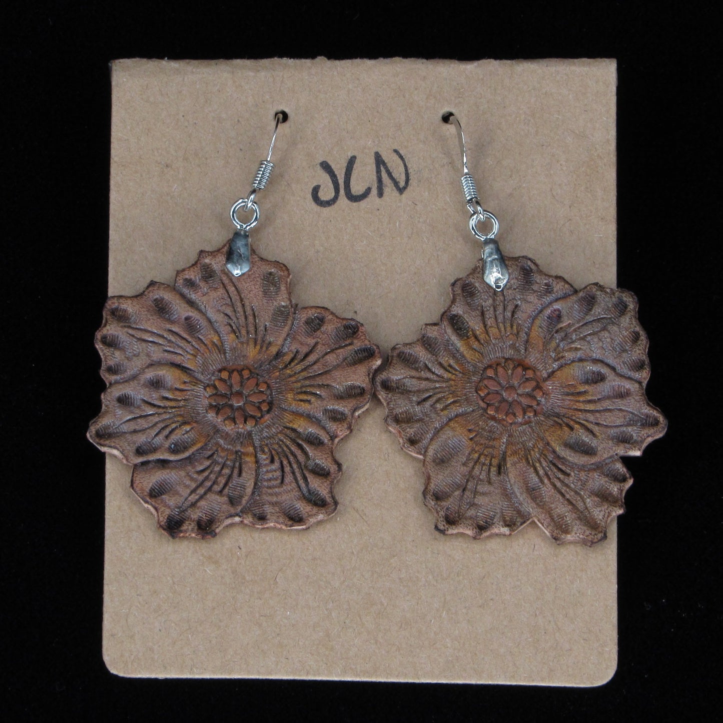 Pair of brown floral earrings on a beige card with 'JLN' branding against a black background.