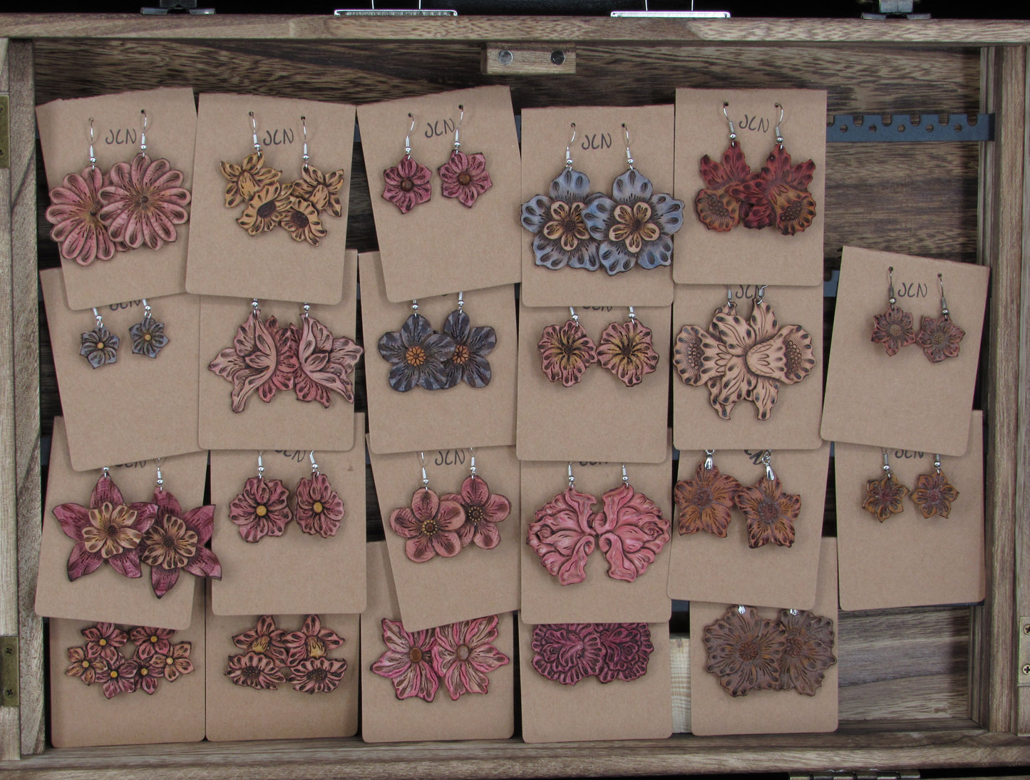 Wooden jewelry box with earring display cards showing various floral earrings.