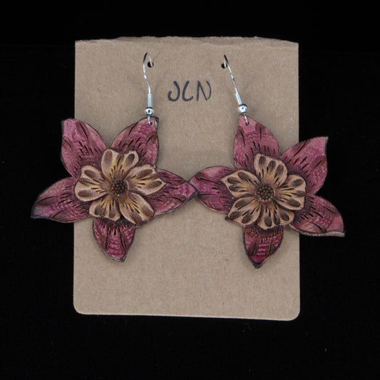 Flower-shaped leather earrings on a brown card with 'JLN' branding against a black background
