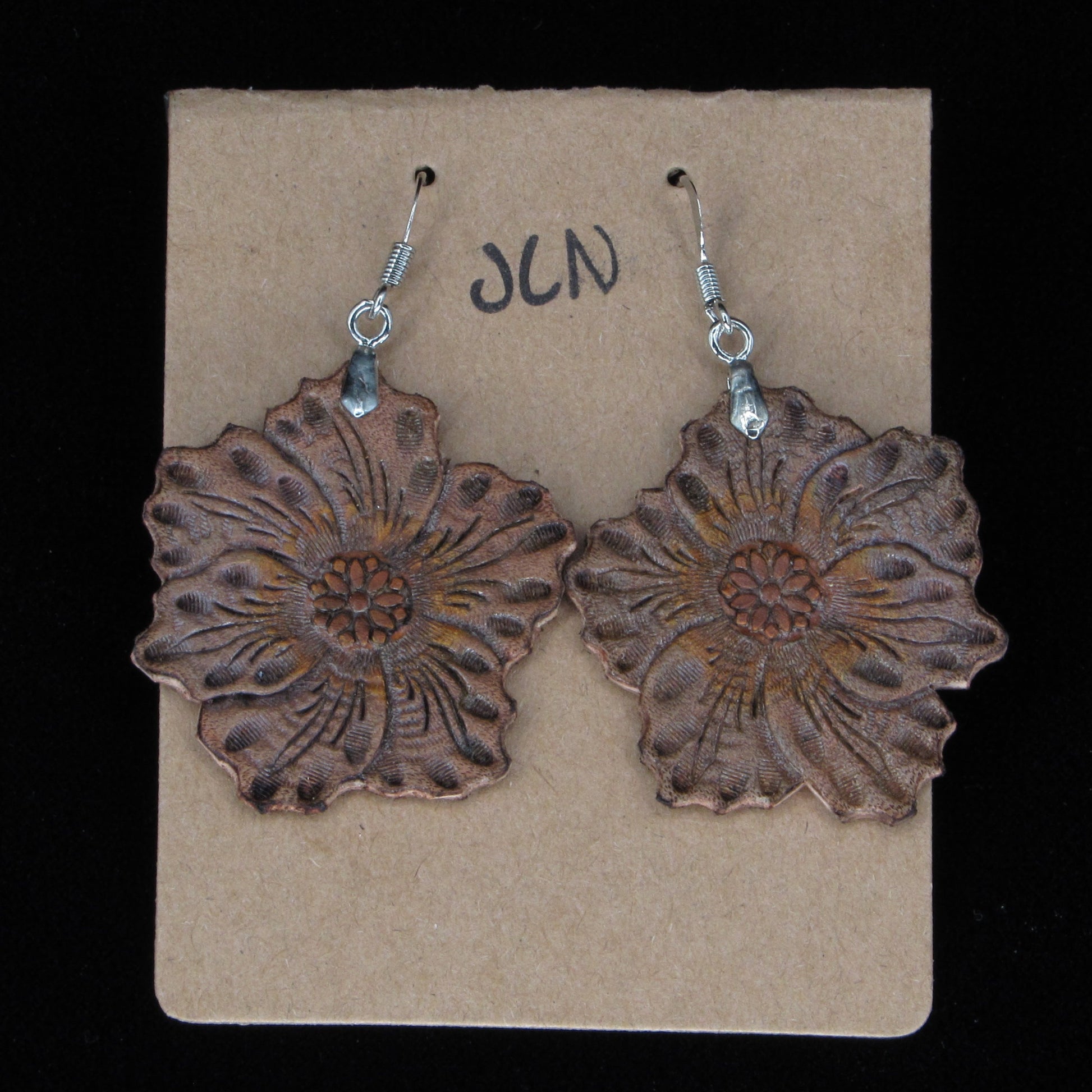 Pair of brown floral earrings on a beige card with 'JLN' branding against a black background.