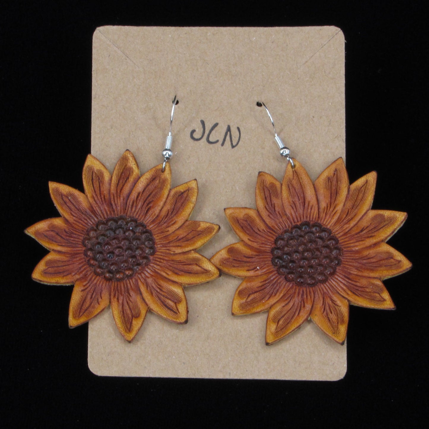 flower shaped leather earrings on a tan card against a black background