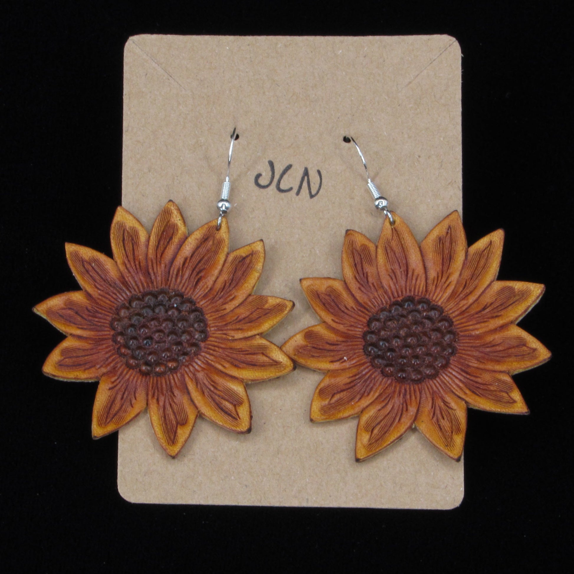 flower shaped leather earrings on a tan card against a black background