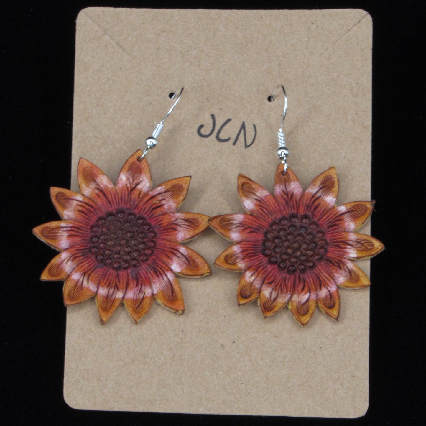 flower shaped leather earrings on a tan card against a black background