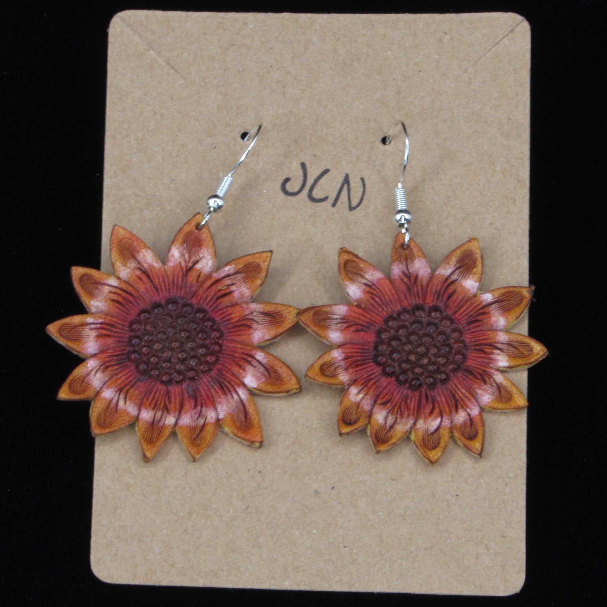 flower shaped leather earrings on a tan card against a black background