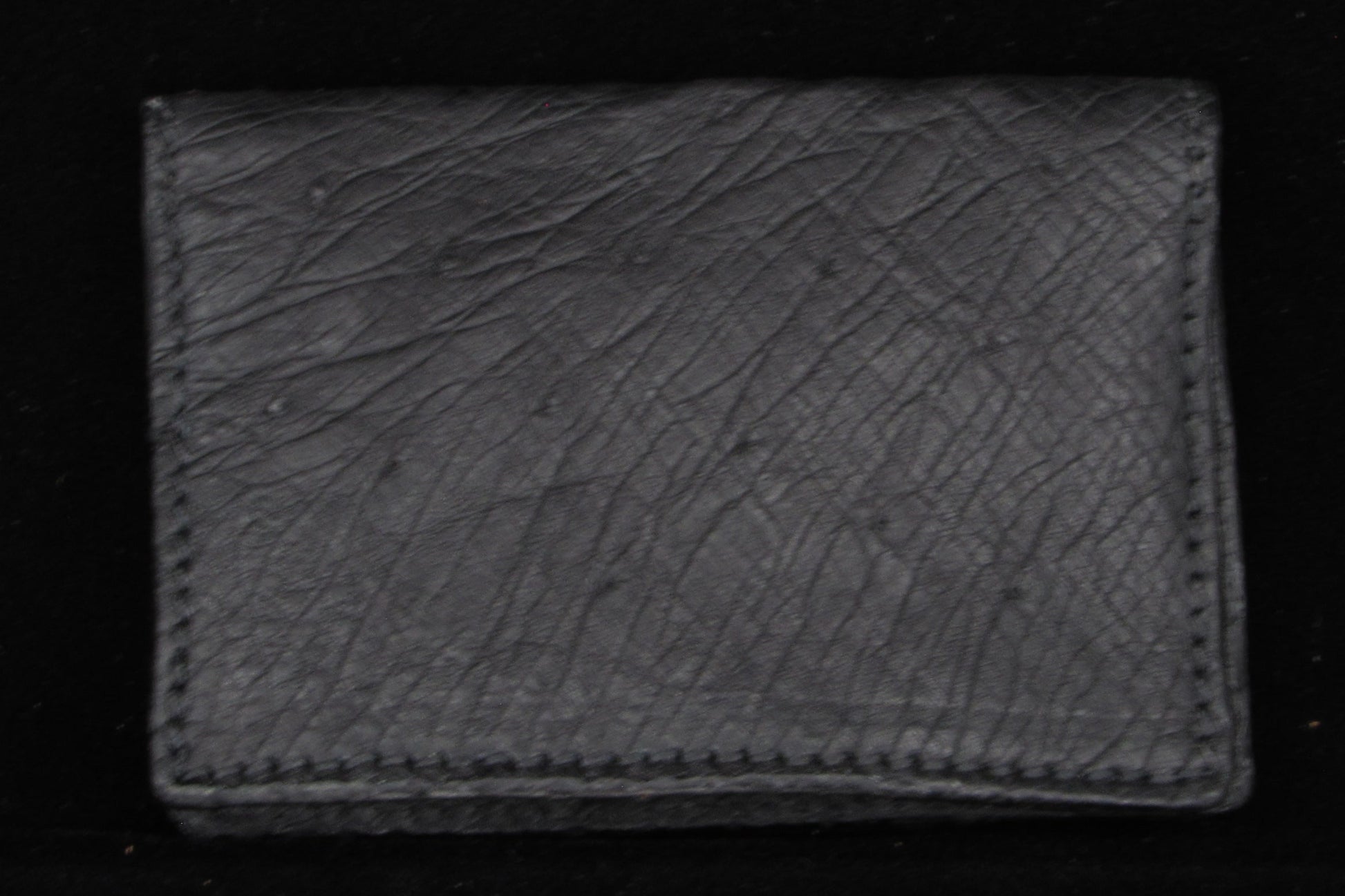 Black  ostrich leather wallet on a black background