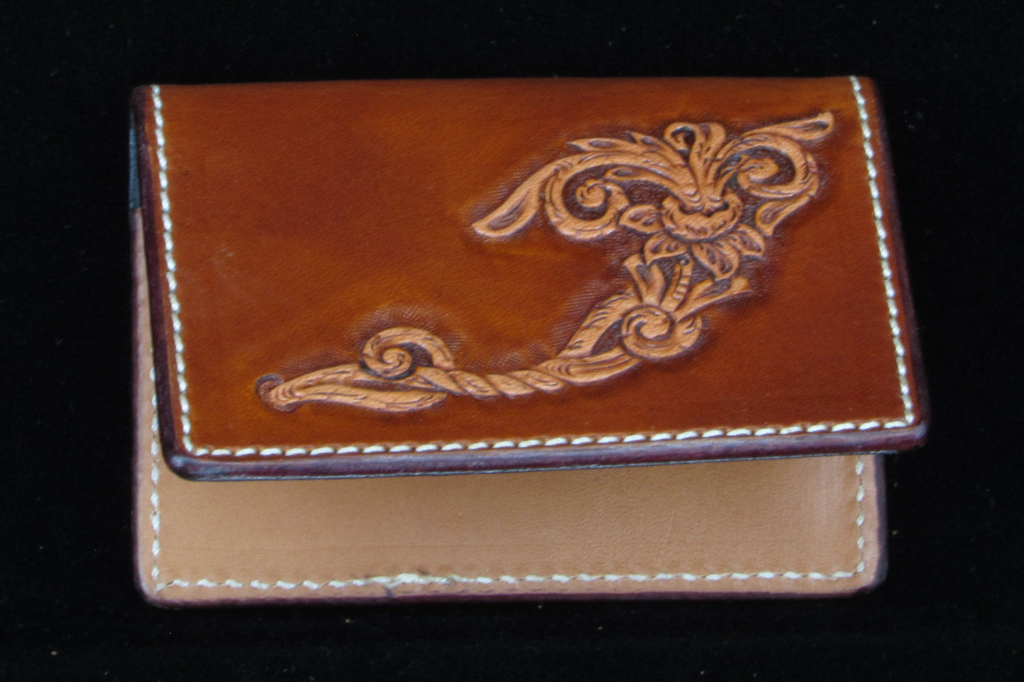 Brown leather wallet with intricate design on a black background