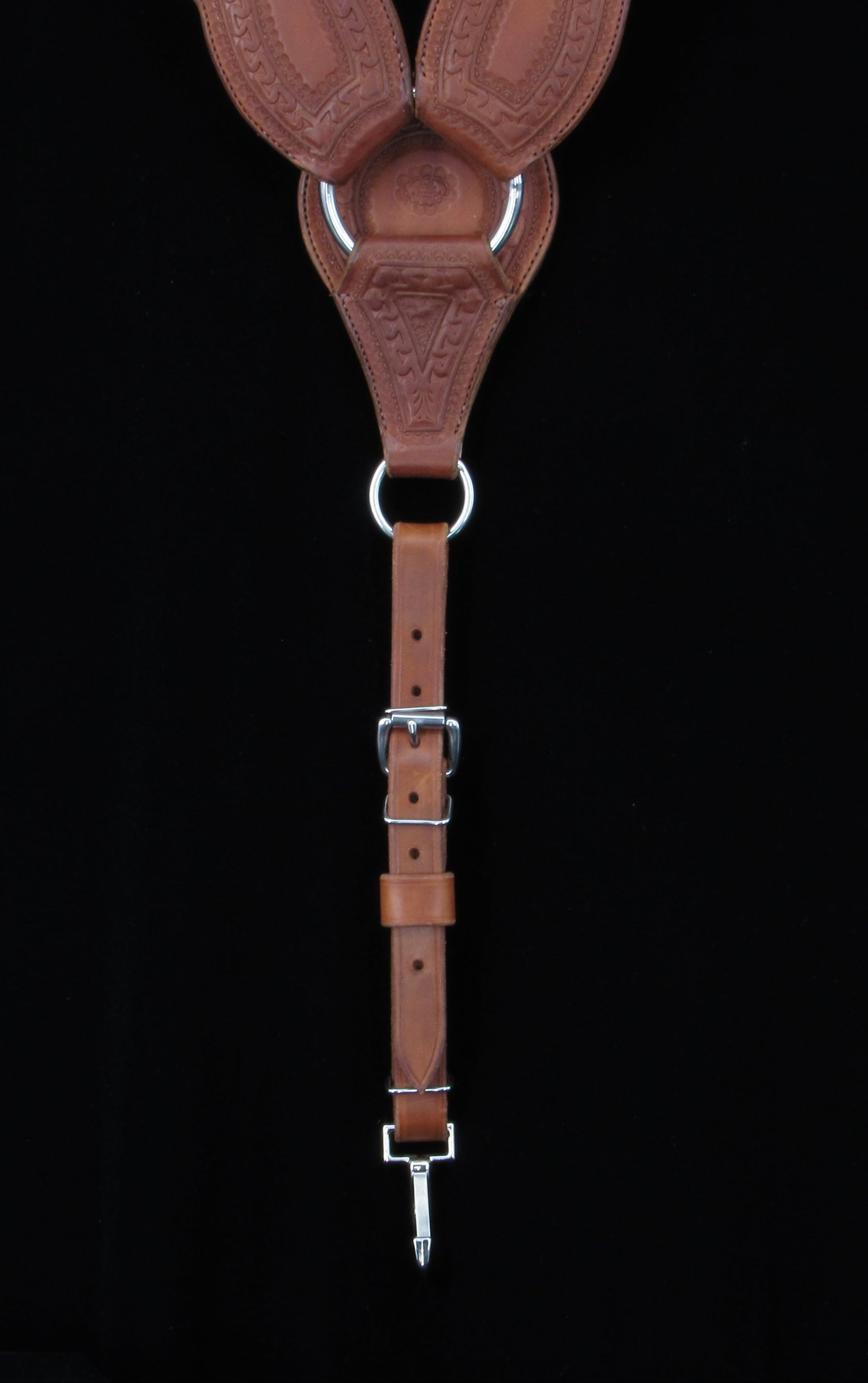 Brown leather breastcollar strap with metal hardware on a black background